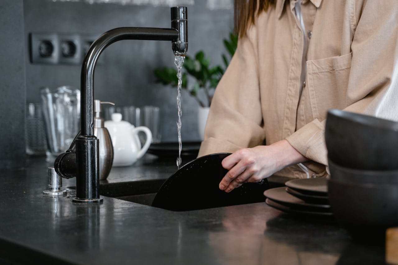 About Close-up of a person washing dishes in a modern kitchen, emphasizing daily chores and routines.